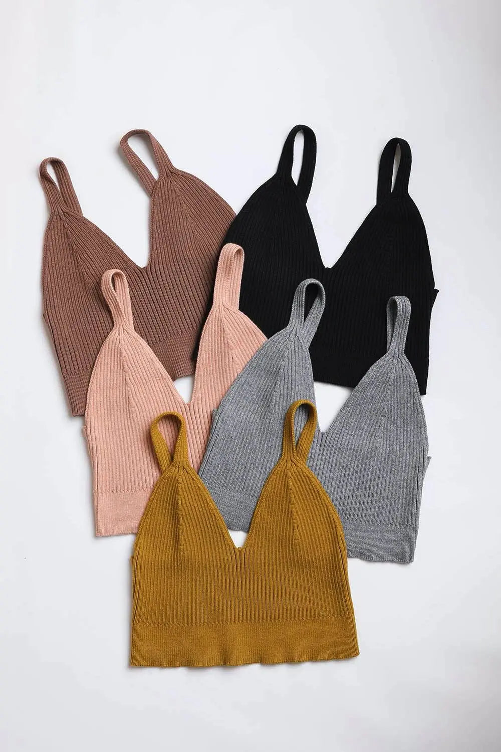 Flat lay of rib knit brami lounge tops in brown blush black gray and mustard showing V-neckline and rib texture
