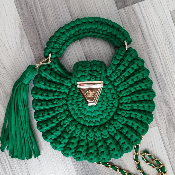 A handmade green crocheted shoulder bag with a top handle, a tassel, 