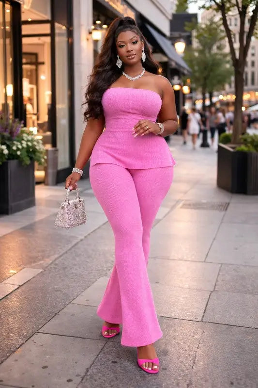 Woman in a pink jumpsuit walking on a city street.