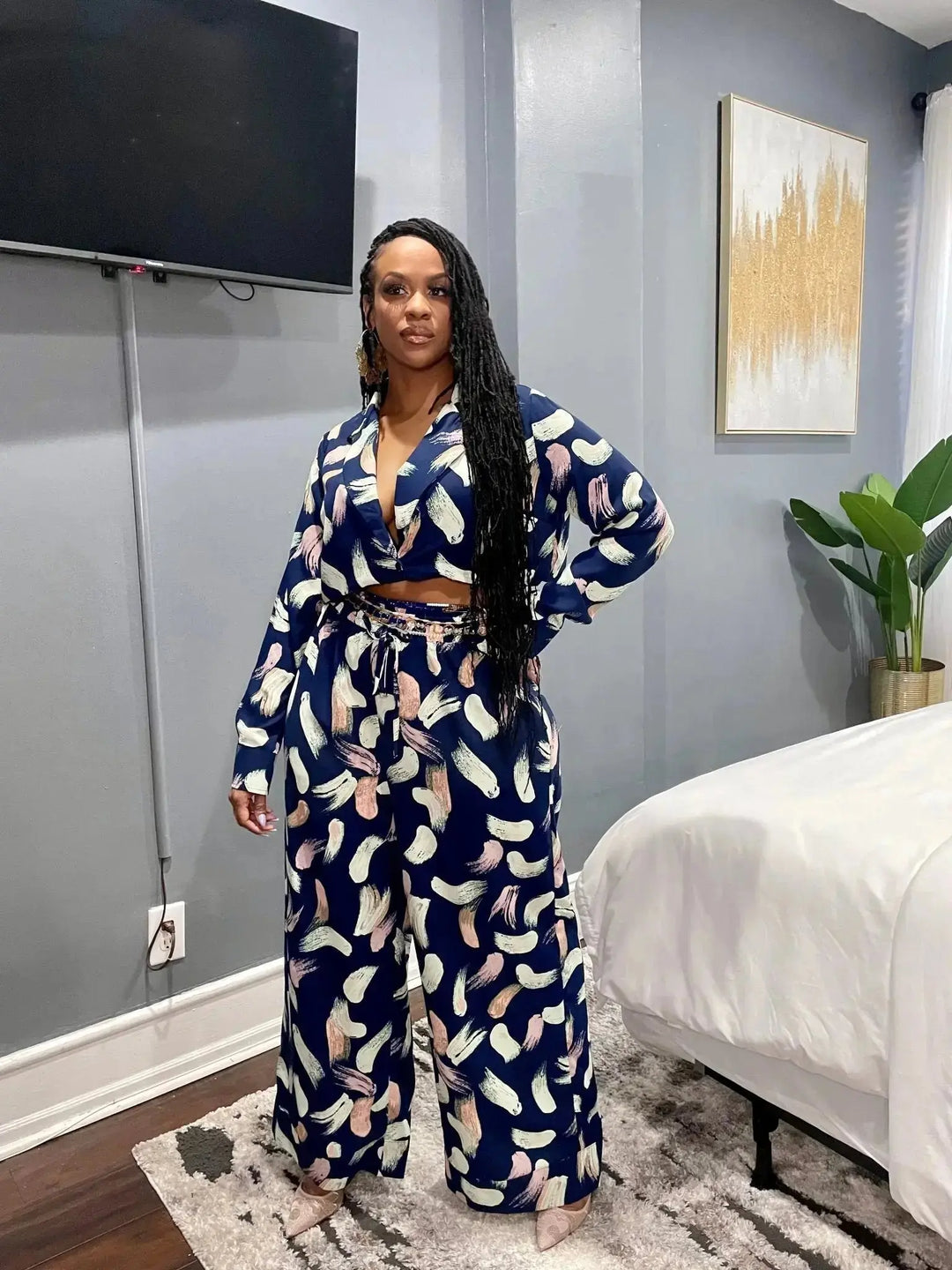 Full length lifestyle shot of Black woman wearing navy abstract print plunge top and matching wide-leg pants
