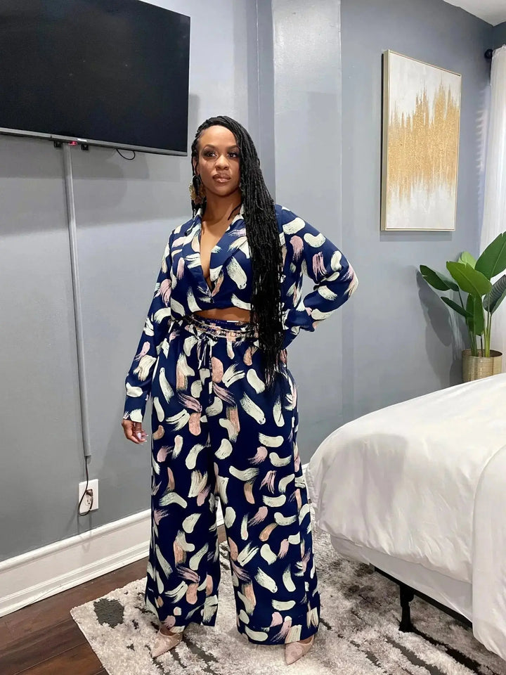 Full length lifestyle shot of Black woman wearing navy abstract print plunge top and matching wide-leg pants