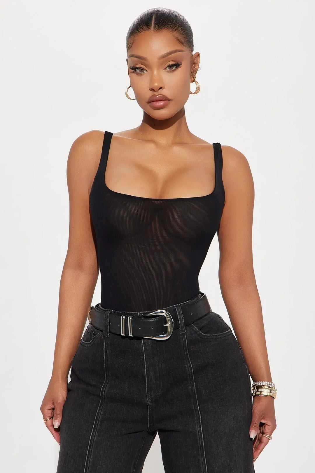 Black mesh thong bodysuit with square neckline styled with black wide-leg jeans and leather belt on model